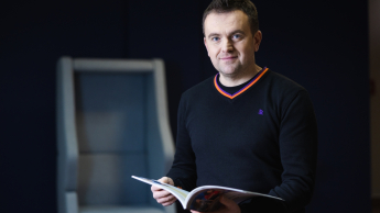 Główna grafika: Opole - specjalność Marketing cyfrowy i grafika reklamowa - mężczyzna w średnim wieku z książką w dłoni