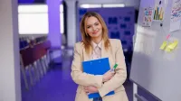Kadry i płace | Uniwersytet WSB Merito Szczecin: Kobieta z teczką i markerem stoi przy tablicy.