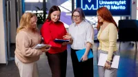 HR Manager | Uniwersytet WSB Merito Szczecin: Cztery kobiety rozmawiają na korytarzu uczelni
