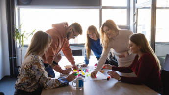 Zarządzanie jakością i produkcją w branży produkcyjnej | Studia podyplomowe w Szczecinie | Uniwersytet WSB Merito Szczecin: Grupa studentów wspólnie pracuje nad kreatywnym projektem, używając kolorowych karteczek i markerów.