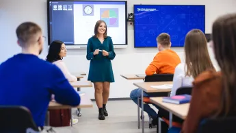 Sztuczna inteligencja w biznesie | Studia podyplomowe w Szczecinie | Uniwersytet WSB Merito Szczecin: Studentka Uniwersytetu WSB Merito prowadzi prezentację w sali wykładowej, a pozostali studenci słuchają jej wystąpienia.