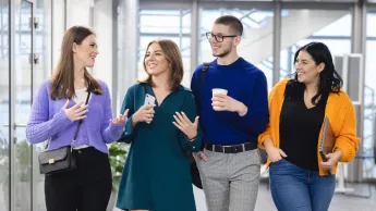 Rachunkowość i sprawozdawczość finansowa | Studia II stopnia w Szczecinie | Uniwersytet WSB Merito Szczecin: Czworo studentów idzie korytarzem uczelni, rozmawiając i śmiejąc się.