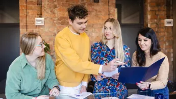 Fintech - innowacje technologiczne na   rynku finansowym | Studia podyplomowe w Szczecinie | Uniwersytet WSB Merito Szczecin: Studenci pracują razem przy stole.