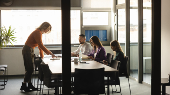 Cztery osoby pracują wspólnie przy stole w sali konferencyjnej.