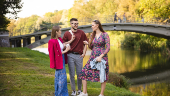 Język niemiecki w komunikacji biznesowej | Uniwersytet WSB Merito Szczecin: Grafika główna: samorząd studencki WSB Merito Szczecin - grupa studentów w plenerze rozmawia nad rzeką
