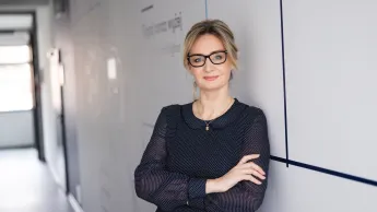 Trychologia | Studia podyplomowe w Szczecinie | Uniwersytet WSB Merito Szczecin: Uczestniczka studiów MBA opiera się o ścianę na korytarzu uczelni- Uniwersytet WSB Merito w Szczecinie 