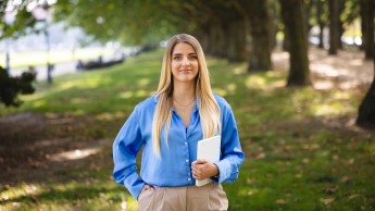 Edukacja dzieci ze specjalnymi potrzebami rozwojowymi | Studia jednolite magisterskie w Szczecinie | Uniwersytet WSB Merito Szczecin: Grafika główna: WSB Merito Szczecin, dla nowych studentów, studentka idzie przez park trzymając książkę w ręku