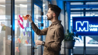 Sztuczna inteligencja dla biznesu | Studia I stopnia w Szczecinie | Uniwersytet WSB Merito Szczecin: Osoba na tle logo Uniwersytet Merito