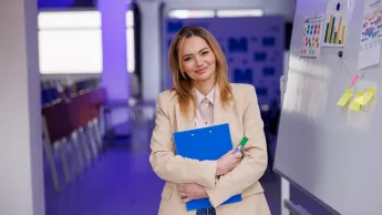 Kadry i płace | Studia podyplomowe w Szczecinie | Uniwersytet WSB Merito Szczecin: Kobieta z teczką i markerem stoi przy tablicy.