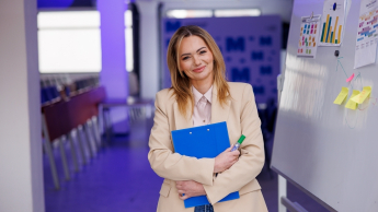 Kadry i płace | Studia podyplomowe w Szczecinie | Uniwersytet WSB Merito Szczecin: Kobieta z teczką i markerem stoi przy tablicy.