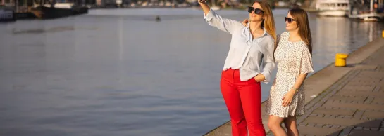 Studia i praktyki za granicą | Uniwersytet WSB Merito Szczecin: Dwie studentki Uniwersytetu WSB Merito Szczecin robią selfie nad Odrą w słoneczny dzień.