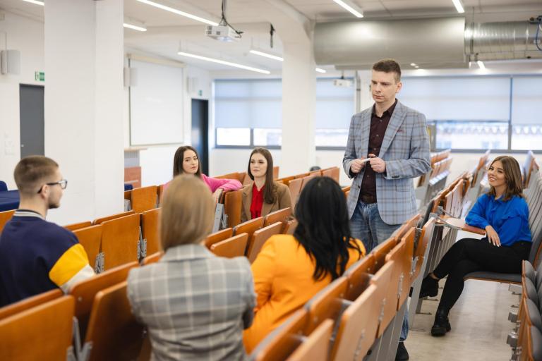 Osiągnięcia naukowe KK | Uniwersytet WSB Merito Szczecin: Wykładowca Uniwersytetu WSB Merito prowadzący dyskusję ze studentami w sali wykładowej.