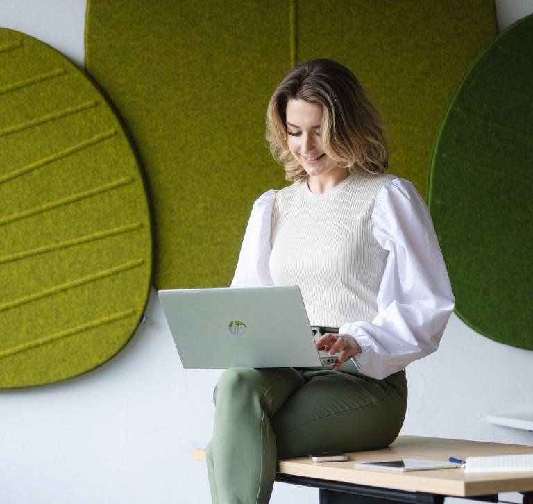 Osiągnięcia naukowe KK | Uniwersytet WSB Merito Szczecin: Studentka Uniwersytetu WSB Merito pracująca na laptopie, siedząc na biurku.