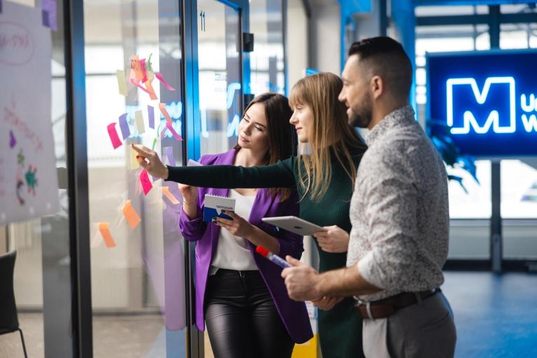 Maturzyści | Uniwersytet WSB Merito Szczecin: Studenci Uniwersytetu WSB Merito pracują nad kreatywnym projektem, organizując pomysły na kolorowych karteczkach.