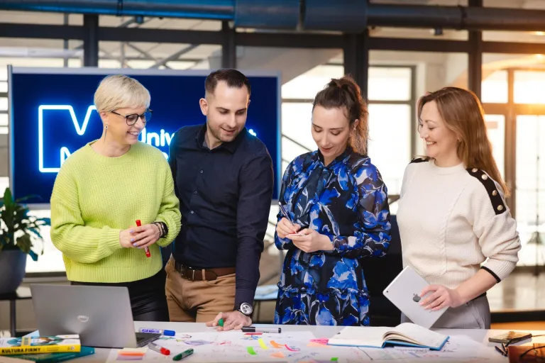 Projekty i usługi | Uniwersytet WSB Merito Szczecin: Cztery osoby pracują nad projektem, otoczone notatkami i materiałami.