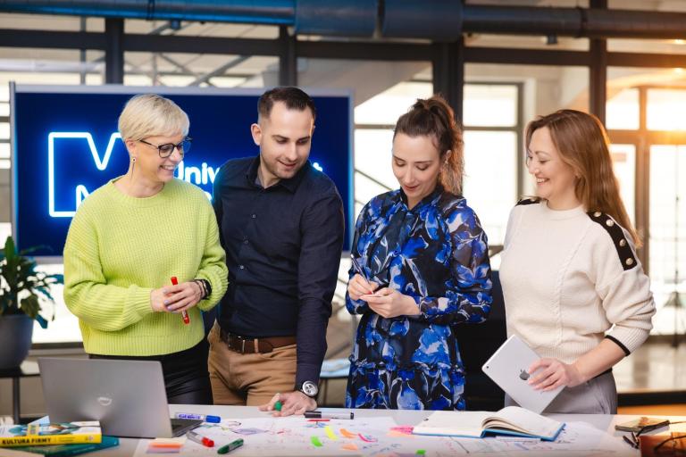 Projekty i usługi | Uniwersytet WSB Merito Szczecin: Cztery osoby pracują nad projektem, otoczone notatkami i materiałami.