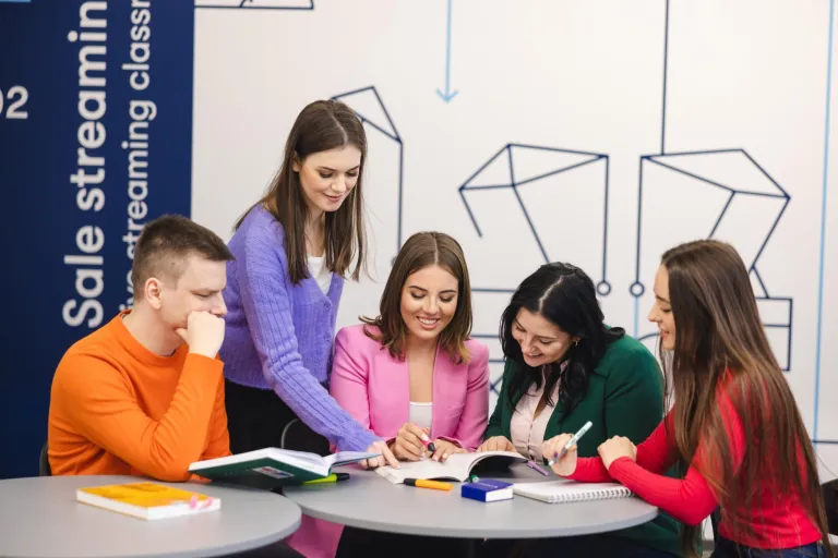 Przygotowanie pedagogiczne dla psychologów | Studia podyplomowe w Szczecinie | Uniwersytet WSB Merito Szczecin: Grupa studentów Uniwersytetu WSB Merito wspólnie pracuje nad materiałami, ucząc się i wymieniając pomysły w nowoczesnej przestrzeni edukacyjnej.