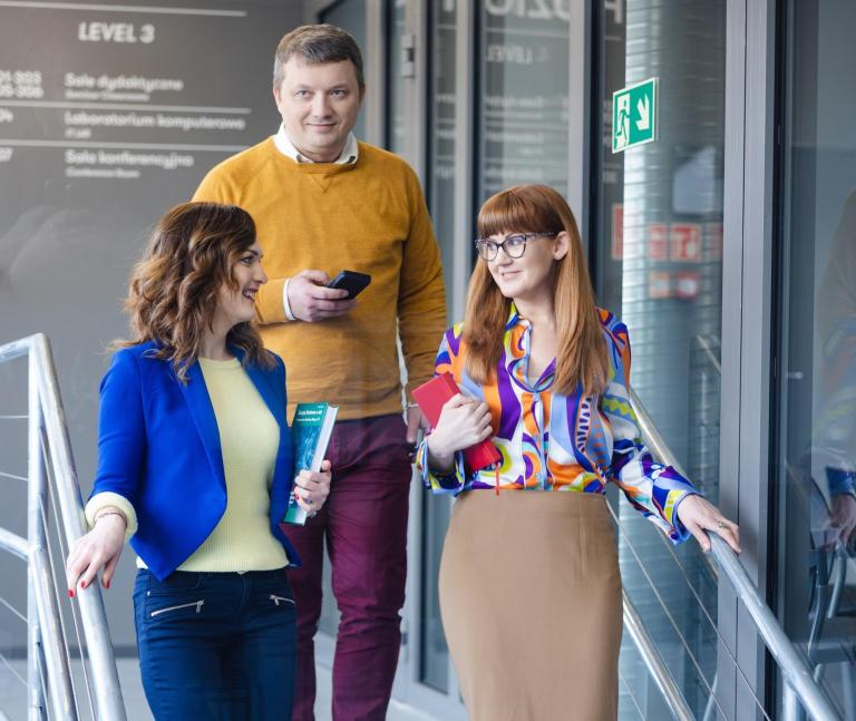 Pośrednictwo pracy | Uniwersytet WSB Merito Szczecin: Trzy osoby schodzą po schodach, prowadząc rozmowę.