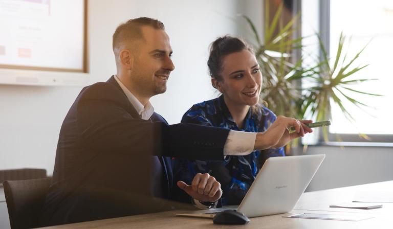 Pośrednictwo pracy | Uniwersytet WSB Merito Szczecin: Dwie osoby pracują przy laptopie, omawiając prezentację.