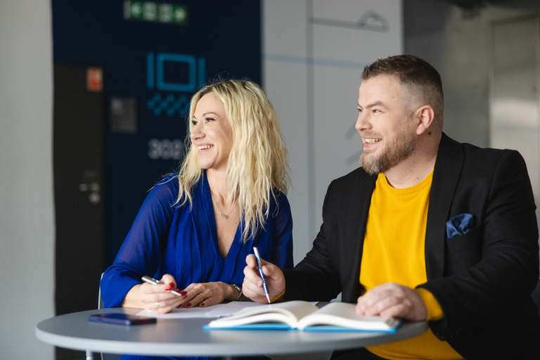 Studia menedżerskie | Studia podyplomowe w Szczecinie | Uniwersytet WSB Merito Szczecin: Uczestnicy studiów MBA piszą notatki przy stole- Uniwersytet WSB Merito w Szczecinie