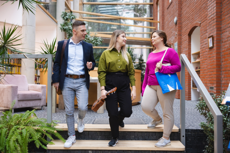 Produkt ,,Warta Klasyki” — ubezpieczenie autocasco dedykowane właścicielom oldtimerów | Uniwersytet WSB Merito Szczecin: 3 osoby rozmawiające na tle uczelni