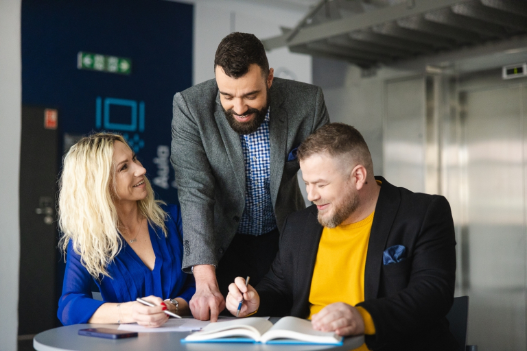 MBA Zarządzanie w podmiotach leczniczych | Studia MBA w Szczecinie | Uniwersytet WSB Merito Szczecin: uczestnicy MBA rozmawiają przy stole czytając notatki