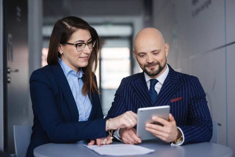 Automatyzacja procesów biznesowych | Studia podyplomowe w Szczecinie | Uniwersytet WSB Merito Szczecin: uczestnicy MBA rozmawiają przy stole i tablecie