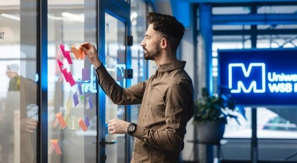 Baza Usług Rozwojowych | Uniwersytet WSB Merito Szczecin: Osoba na tle logo Uniwersytet Merito