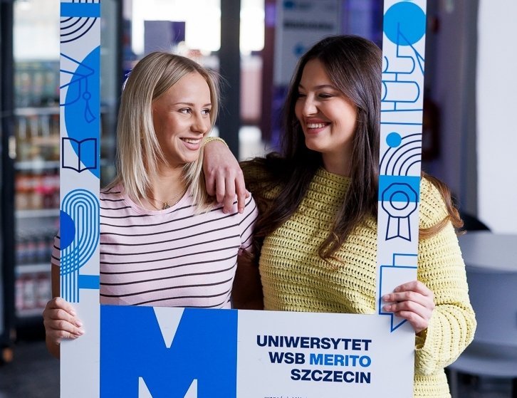 Dietetyka kliniczna | Studia I stopnia w Szczecinie | Uniwersytet WSB Merito Szczecin: Dwie dziewczyny pozują z dużą ramką uczelni.