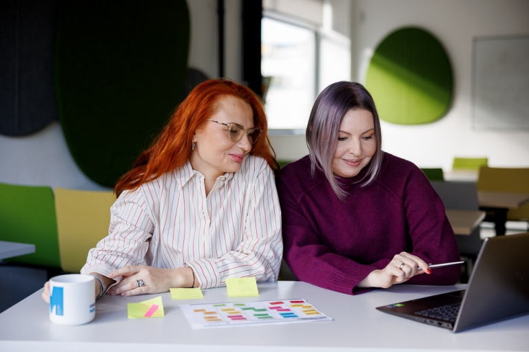 Wczesne wspomaganie rozwoju | Studia podyplomowe w Szczecinie | Uniwersytet WSB Merito Szczecin: Dwie kobiety pracują przy laptopie i kolorowych notatkach.