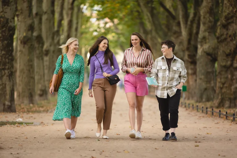 Dietetyka i promocja zdrowia | Studia I stopnia w Szczecinie | Uniwersytet WSB Merito Szczecin: Czwórka młodych osób spaceruje alejką w parku, rozmawiając i śmiejąc się.