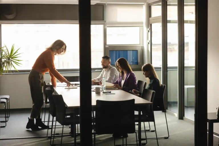 Psychologia w zarządzaniu | Studia II stopnia ze studiami podyplomowymi  | Uniwersytet WSB Merito Szczecin: Cztery osoby pracują wspólnie przy stole w sali konferencyjnej.