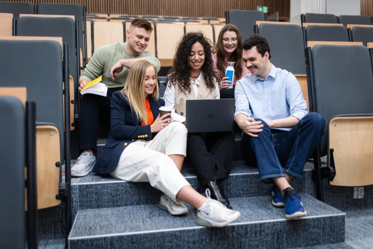 Zarządzanie | Studia II stopnia ze studiami podyplomowymi w Szczecinie | Uniwersytet WSB Merito Szczecin: Studenci pracują zespołowo przy laptopie w auli wykładowej.