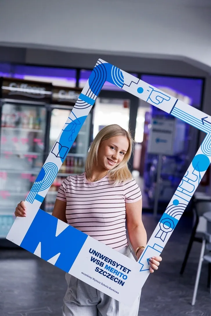 Językoznawstwo stosowane i glottodydaktyka | Uniwersytet WSB Merito Szczecin: Dziewczyna pozuje z dużą ramką uczelni.