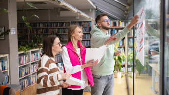 Sprzedaż i e-commerce | Studia I stopnia w Toruniu | Uniwersytet WSB Merito w Toruniu: Główna grafika: Toruń - studia I stopnia - grupa uśmiechniętych studentów w bibliotece