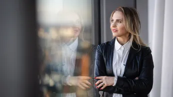Wycena nieruchomości (online) | Studia podyplomowe w Toruniu | Uniwersytet WSB Merito w Toruniu: Główna grafika: Toruń - studia podyplomowe - Uczestniczka studiów podyplomowych patrząca przez okno
