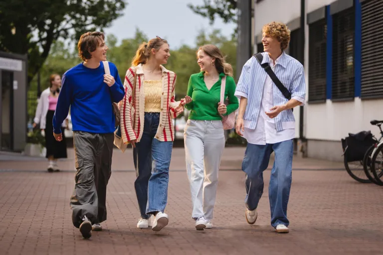 Kierunki inżynierskie - mniejsza inwestycja, ten sam zwrot! | Uniwersytet WSB Merito w Toruniu: Studenci idą i rozmawiają przed uczelnią