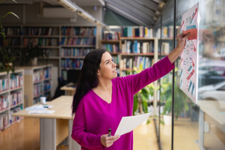 Kierunki inżynierskie - mniejsza inwestycja, ten sam zwrot! | Uniwersytet WSB Merito w Toruniu: Główna grafika: Toruń - studia I stopnia - studentka pracująca przy tablicy w bibliotece