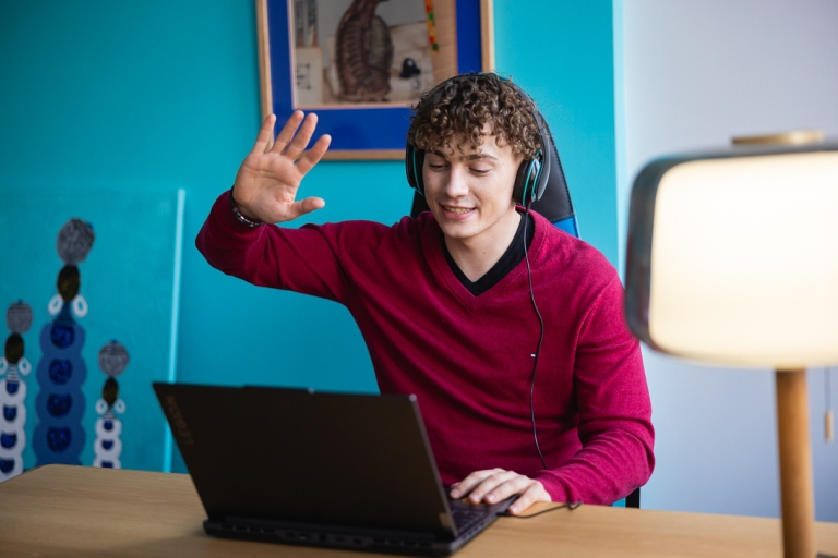 Projektowanie komunikacji produktowej | Studia I stopnia w Toruniu | Uniwersytet WSB Merito w Toruniu: Główna grafika: Toruń - studia I stopnia - student witający się z uczestnikami online zajęć