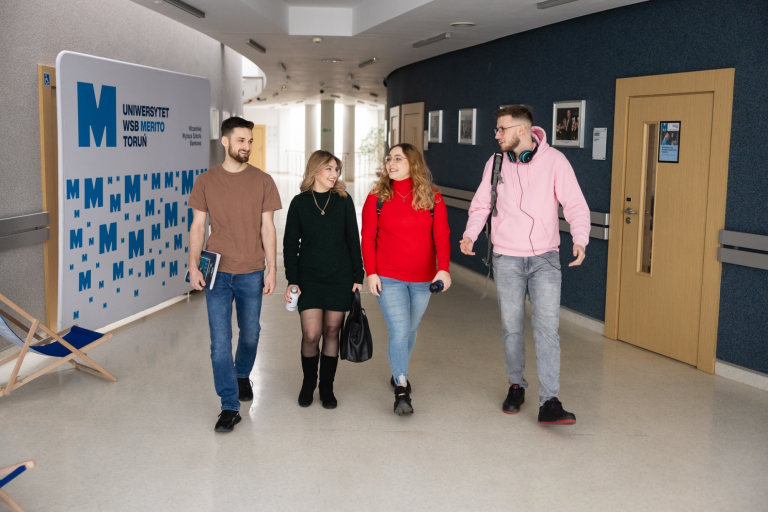 SPINAKER UWSB – Intensywne międzynarodowe programy kształcenia | Uniwersytet WSB Merito w Toruniu: czwórka studentów na korytarzu uniwersytetu