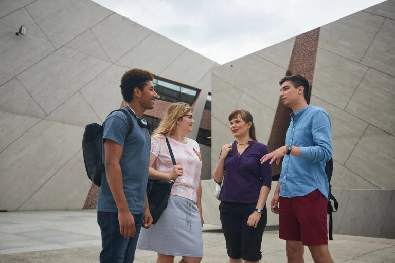 Projektowanie marki i wizerunku firmy | Studia I stopnia w Toruniu | Uniwersytet WSB Merito w Toruniu: Głowna grafika: Toruń- studia jednolite magisterskie -  grupa studentów a w tle budynek 