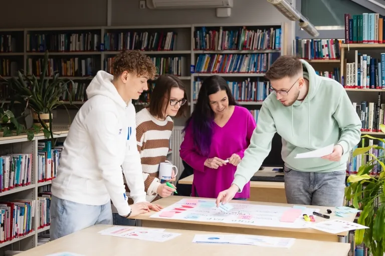 Główna grafika: Toruń - studia I stopnia - grupa  studentów pracująca w bibliotece