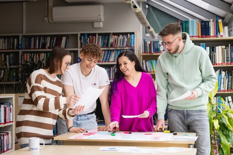 Rachunkowość przedsiębiorstw i kontrola finansowa | Studia II stopnia ze studiami podyplomowymi  | Uniwersytet WSB Merito w Toruniu: Główna grafika: Toruń - studia I stopnia - grupa uśmiechniętych studentów w bibliotece