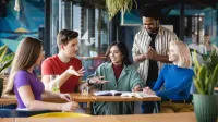 Strategiczny marketing internetowy | Studia I stopnia w Warszawie | Uniwersytet WSB Merito Warszawa: Studenci WSB Merito Warszawa w wesołej atmosferze rozmawiają przy stoliku
