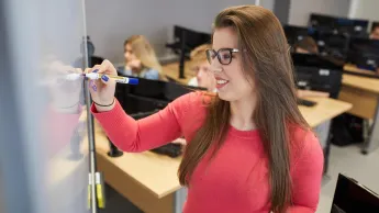 Inżynieria baz danych | Studia I stopnia w Warszawie | Uniwersytet WSB Merito Warszawa: Studentka przy tablicy w sali komputerowej