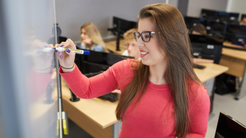 Inżynieria baz danych | Studia I stopnia w Warszawie | Uniwersytet WSB Merito Warszawa: Studentka przy tablicy w sali komputerowej