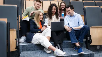 Zarządzanie przedsiębiorstwem | Studia I stopnia w Warszawie | Uniwersytet WSB Merito Warszawa: Grupa studentów siedzących na schodach 