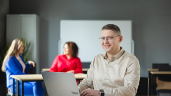 Projektowanie gier komputerowych | Studia podyplomowe w Warszawie | Uniwersytet WSB Merito Warszawa: uśmiechnięty mężczyzna siedzący przed laptopem