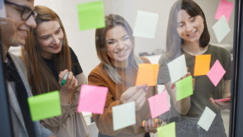 Team coaching i facylitacja | Studia podyplomowe w Warszawie | Uniwersytet WSB Merito Warszawa: grupa osób przyklejająca karteczki