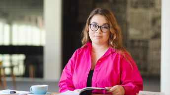 Akademia Lidera Merito | Uniwersytet WSB Merito Warszawa: Studentka siedzi przy stole.